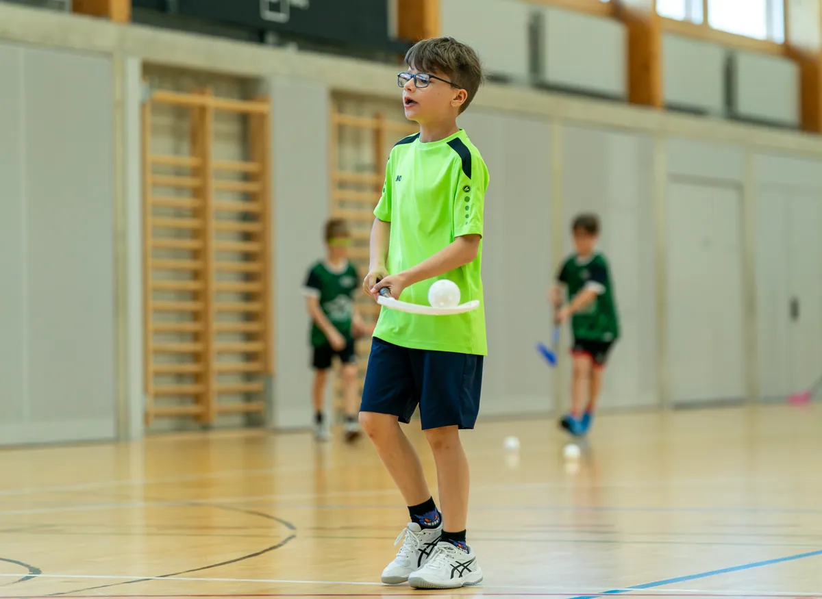 Junger Unihockeyspieler konzentriert mit Ball und Stock